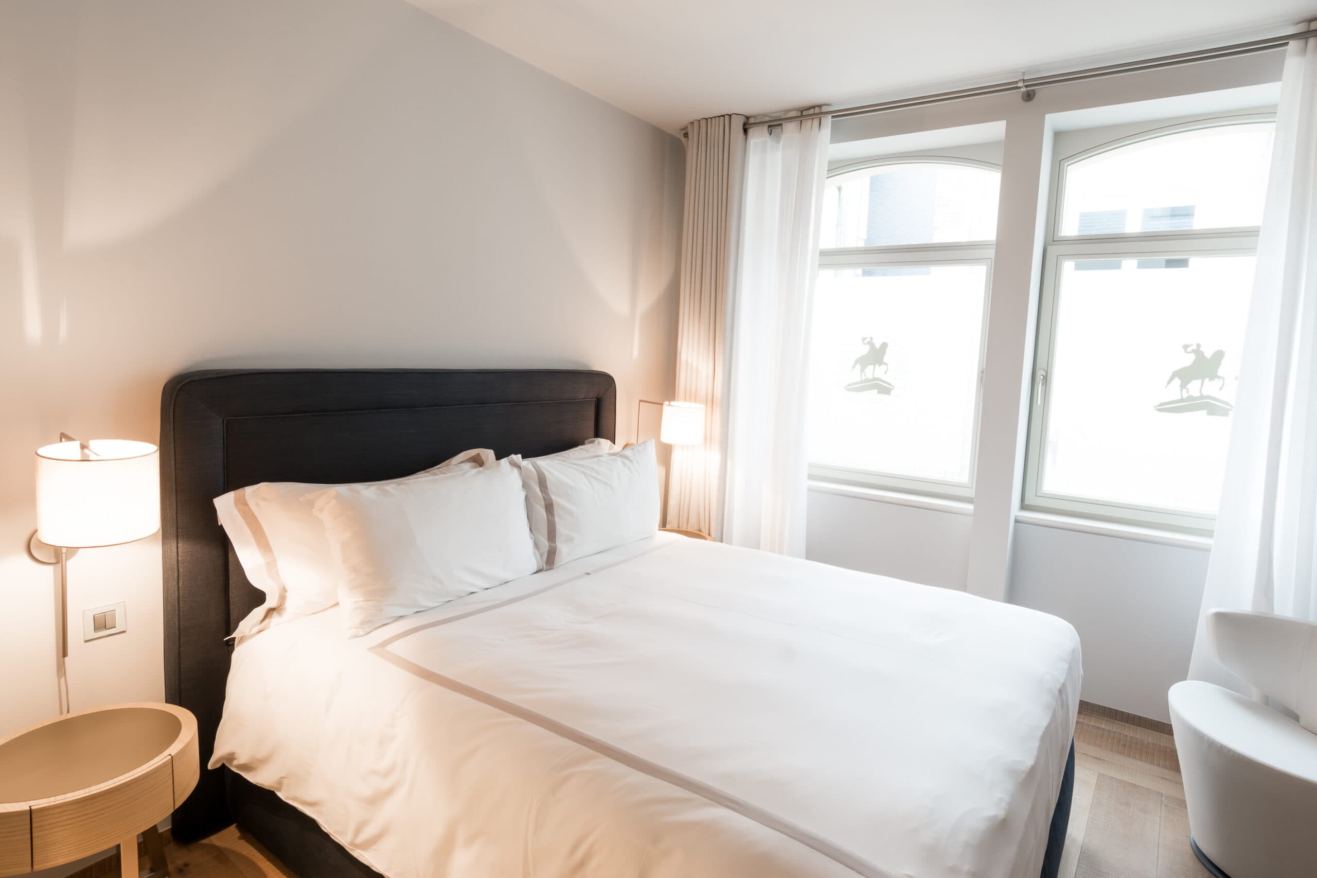 A bright bedroom with tall windows at Guillaume Suites.